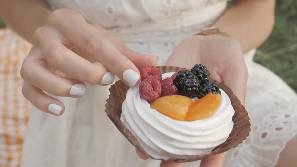 Woman Holds in Her Hand a Cake, Meringue with Berries. He Takes One Raspberry.