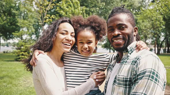 Close Up Portrait of Laughing African Couple and Their Little Daughter in the Park