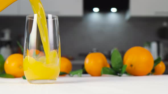 Orange juice pouring into glass on white table