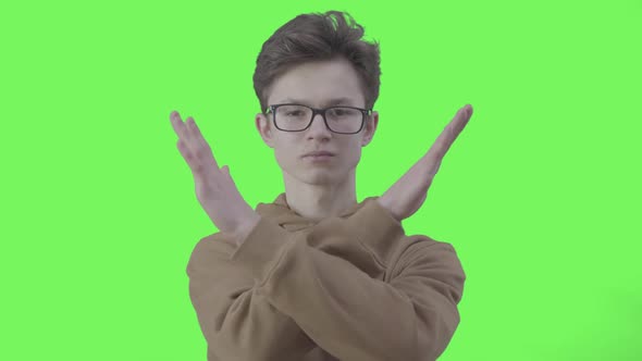 Serious Boy in Eyeglasses Making No Gesture at Green Background. Portrait of Confident Caucasian