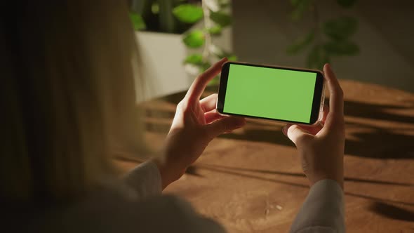 Handheld Over the Shoulder Close Up Shot of a Woman Holding Smart Phone with Green Screen Chroma Key