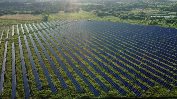 Top view of a massive photovoltaic power station located in a field at sunset