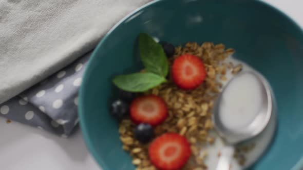 Video of cereals and fruit in ceramic bowl on white kitchen worktop