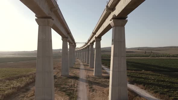 Slow flight between the tall pillars of a train bridge at sunset in Israel