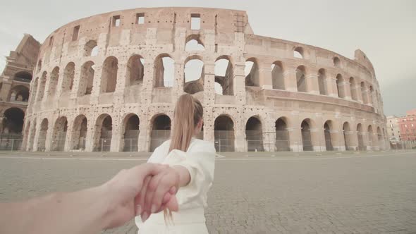 Woman Holds Hand of Man Walking to Large Colosseum in Rome