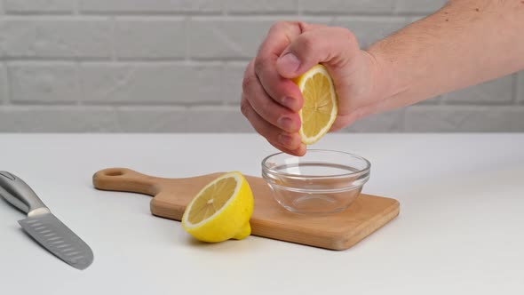 Squeez a half cut lemon over a glass saucer on a cutting board.