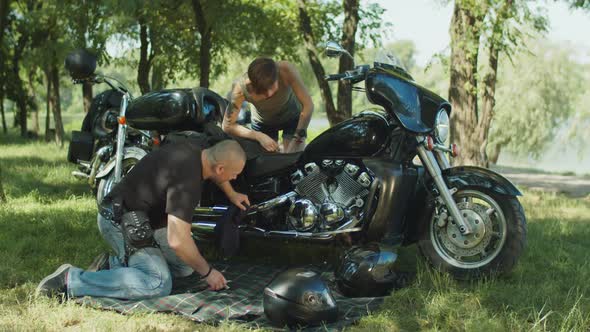 Man Helping Woman To Repair Motorbike Outdoors