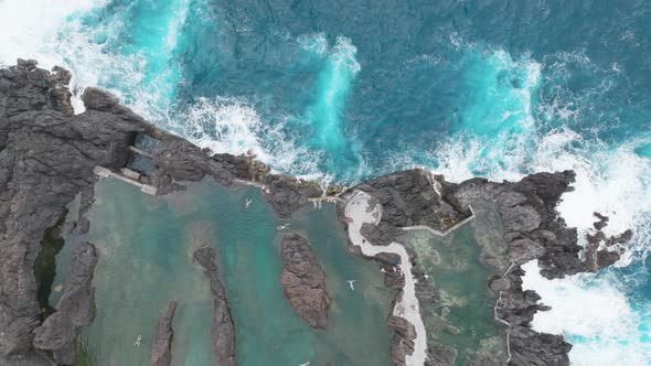 Overhead View Of People Swimming On Natural Swimming On Lava Rock In Porto Moniz, Madeira, Portugal.