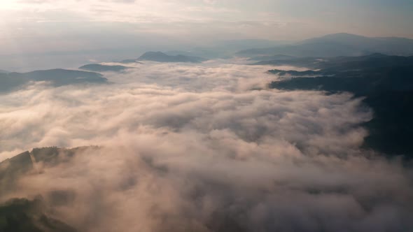 Low clouds and morning mists over mountain slopes at sunrise