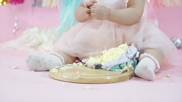 Cute Toddler Eating and Playing with Birthday Cake in Pink Background with Balloons and Decorations