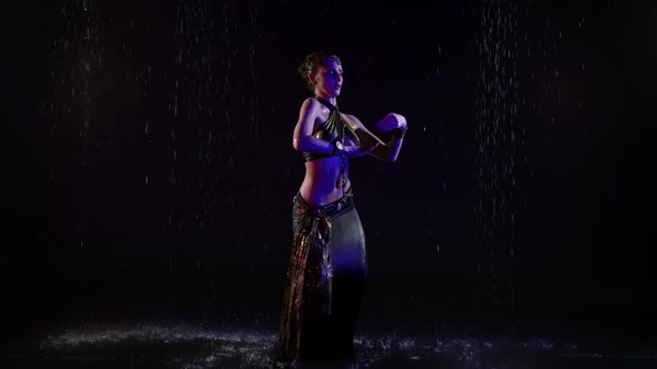 Enigmatic Arabic Dancer Woman is Dancing Under Rain at Night Moving Slowly