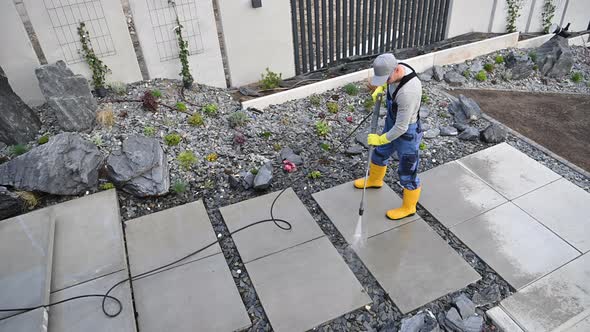 Men Washing His Backyard Garden Concrete Path and Stairs Using Pressure Washer