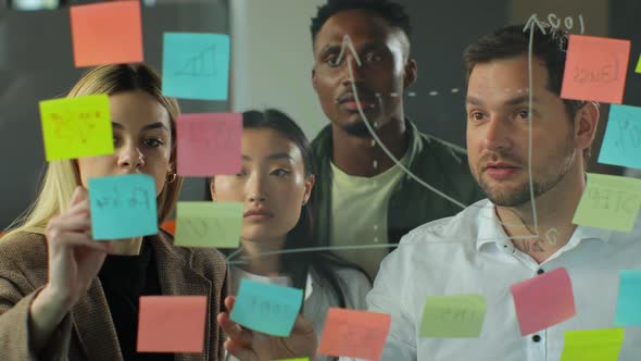 Business Team Meeting in the Office and Discussing a Project Together They are Pointing at Sticky