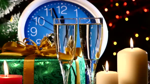 Glasses with Champagne on New Year Eve Against Wall Clock, Candles, Presents, Bokeh, Garland, on