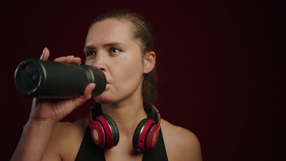 A Female Athlete Drinks Water From a Bottle