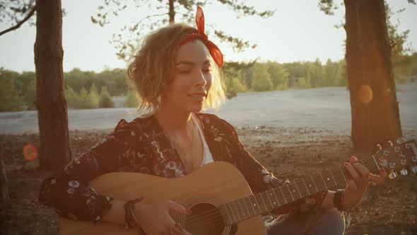 Young Attractive Girl Plays Acoustic Guitar in Camping