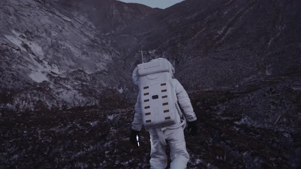 an Astronaut at Dusk with a Lantern in His Hand Climbs the Hill