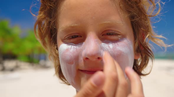 Mother Applying Sunscreen Cream on Baby Boy's Face on the Beach at the Seaside