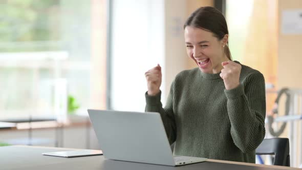 Young Woman Celebrating Success on Laptop