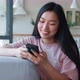Front View of a Serene Happy Darkhaired Asian Woman Using Her Smartphone for Texting Browsing Mobile - VideoHive Item for Sale