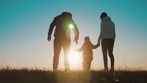Happy Young Family Together with Their Little Child at Sunset