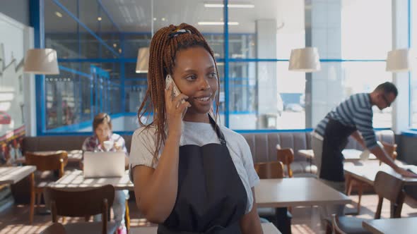 African Waitress Taking Order on Phone in Restaurant