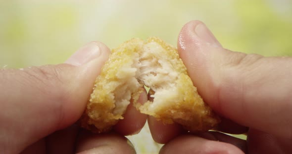 Two Hands Tearing Apart A Piece Of Fried Chicken Nugget On The Table Dollying In To A Macro Shot