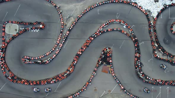 Aerial top view of the go-kart track from the drone. Kart racers drive on the open track.