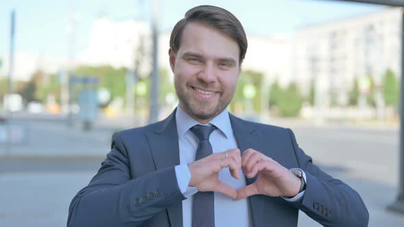 Loving Businessman showing Heart Shape by Hands Outdoor