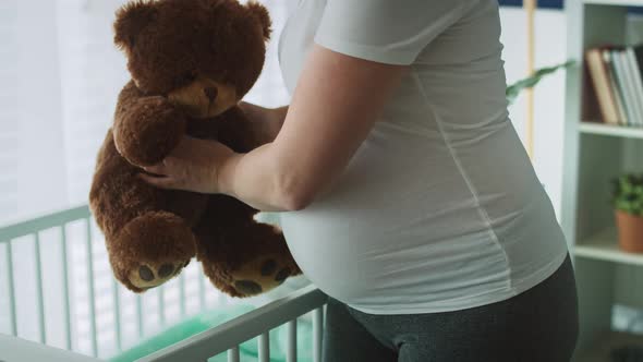 Video of pregnant woman putting teddy bear to the crib. Shot with RED helium camera in 8K  