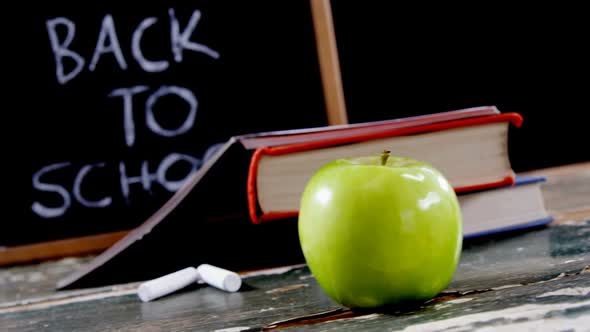 Apple, book, chalk and slate on table