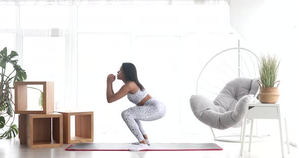 Sporty young black woman making lunges training at home.