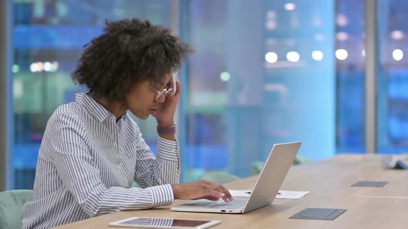 Stressed African Businesswoman with Laptop Having Headache in Office 