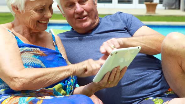 Senior couple using digital tablet on lounge chair