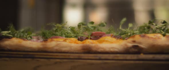 Close up of traditional al taglio pizza with orange sauce, roast beef and green toppings.