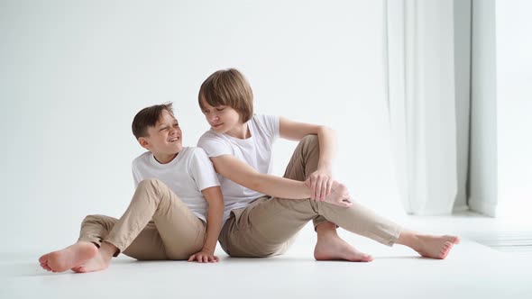 Two Boys in White Tshirts Pose for a Photographer in a Photo Studio