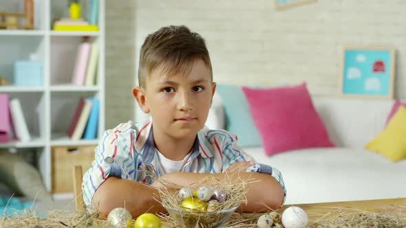 Little Boy Posing at Desk with Easter Eggs on Hay alt