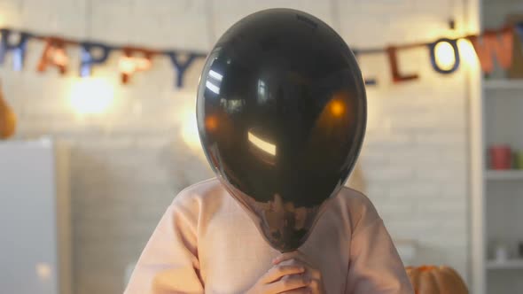 Pretty Little Child Hiding Behind Black Balloon and Showing Claws, Halloween