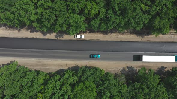 Aerial Shot of Car with Truck Driving on New Asphalt Road Through Forest