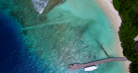 Daytime birds eye tourism shot of a white sand paradise beach and blue water background in 4K