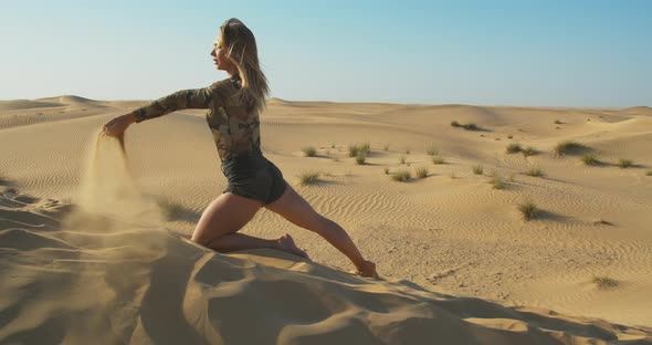 Young Model is Standing on One Knee and Pouring Sand in Great Sandy Desert