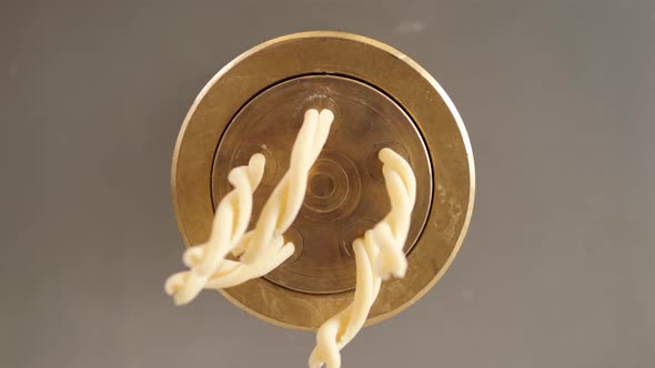 Tortiglioni Cazarece Spaghetti Pasta Falling From a Spout As They Travel Along the Production Line