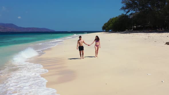 Guy and girl tan on beautiful coast beach time by blue ocean and white sand background of Gili Air n