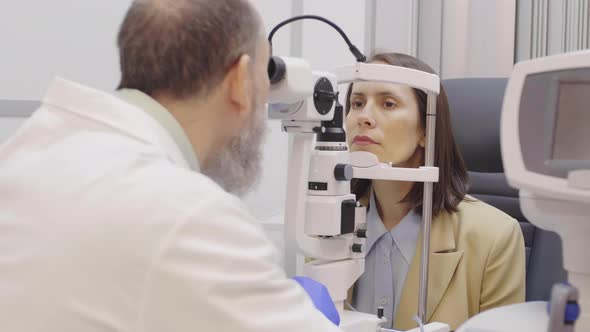 Optometrist Using Slit Lamp Biomicroscope for Eye Exam of Female Patient