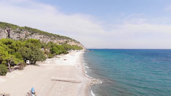 Aerial View of the Mountain Coast with Buildings Among the Trees and the Bright Blue Sea with