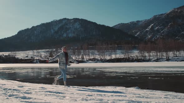 Cheerful Woman Runs Near the River in Winter and Laughs