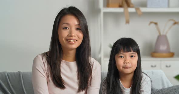 Asian Mother with Little Daughter Girl Child Looking at Web Camera Waving Their Hands Saying Hello