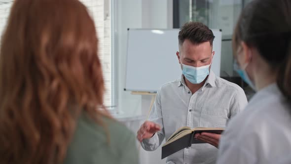 Young Man Observes Precautions and Wears Medical Mask on His Face While Reading Bible with Christian