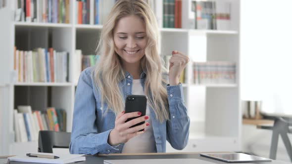 Blonde Woman Excited for Success while Using Smartphone