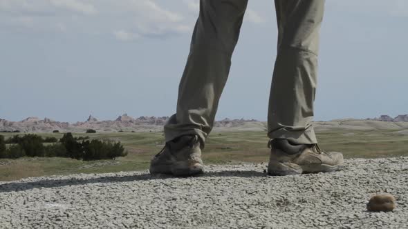 Hiker walks past camera and pauses - legs and boots visible - Badlands National Park, South Dakota